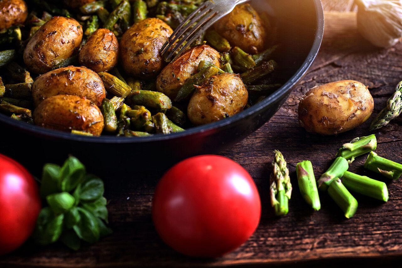 Potatoes fried with asparagus in a pan with spices and tomatoes