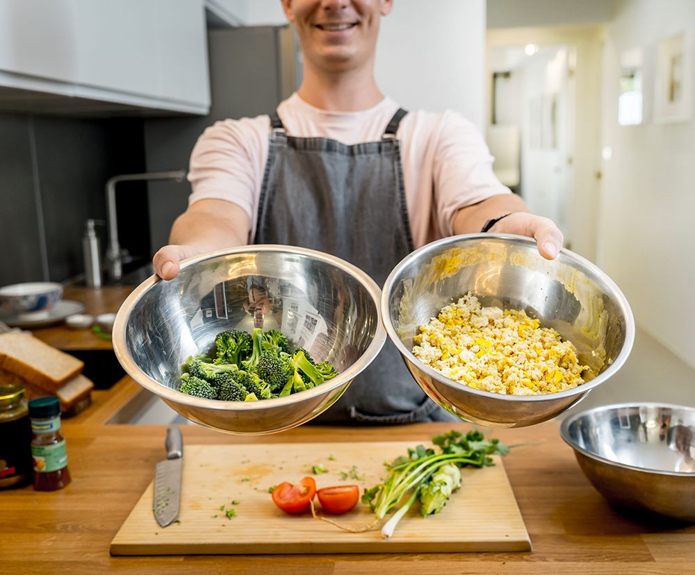Persona preparando alimentos vegetales con brócoli y tofu