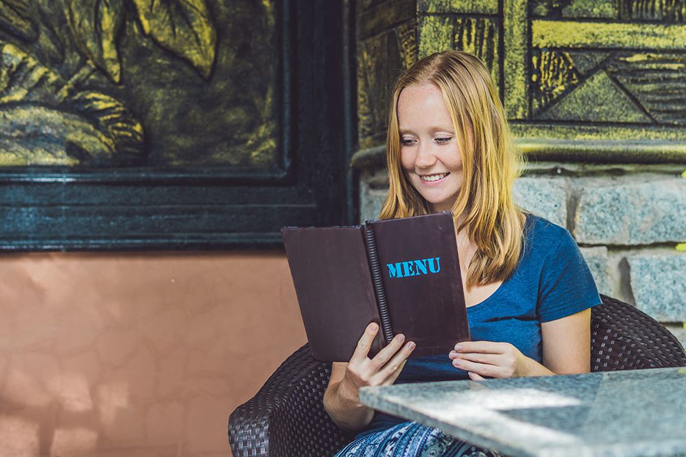 Beautiful woman ordering from menu in restaurant and deciding what to eat.